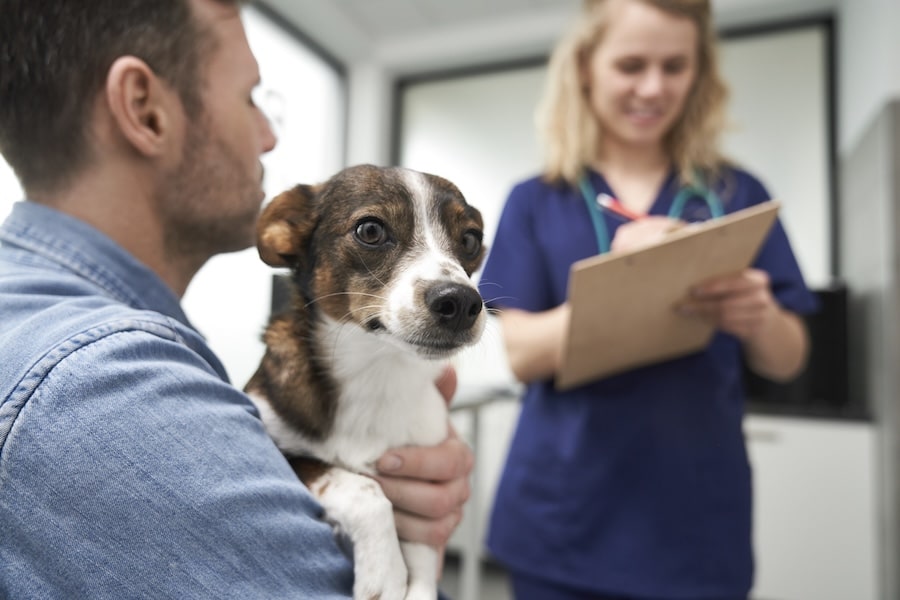 A man holding his dog while at the vet. 